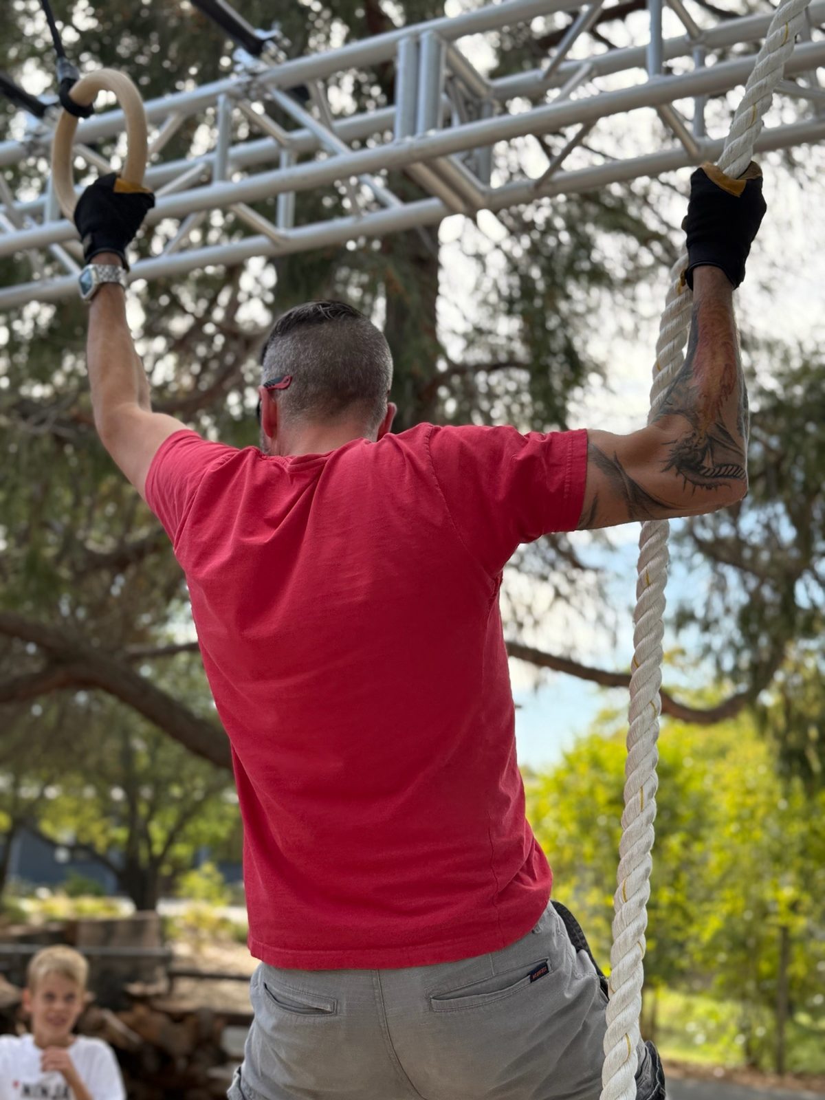 Young ninja swinging across hanging obstacles